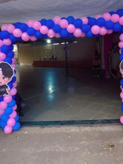 A fun balloon gate for a baby shower entrance, designed with a pink and blue color scheme and featuring cute cartoon character cutouts.