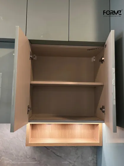 A look inside an overhead cabinet, showing the quality of the internal finish and the soft-close hinge mechanism. The open niche below with integrated lighting is perfect for display or easy access to frequently used items.