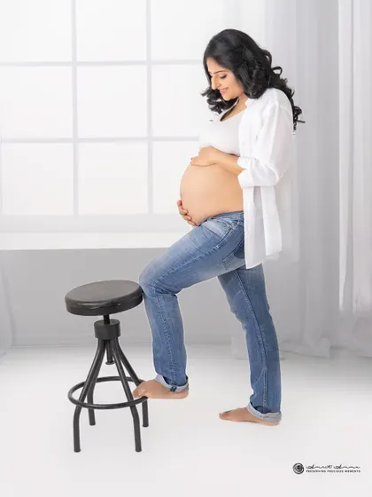 A simple, strong, and beautiful solo portrait. The clean white background and casual styling put all the focus on the beautiful shape of the baby bump.
