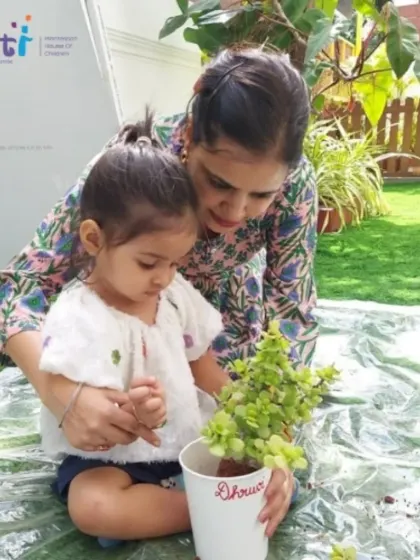 A teacher helps a child pot her own plant, which she can take home. This gives her a sense of ownership and continued responsibility.