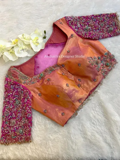 A vibrant orange and pink blouse with heavily embroidered floral sleeves.