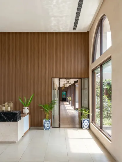 Natural light floods the reception area, highlighting the height of the space and creating a connection to the outdoor courtyards.