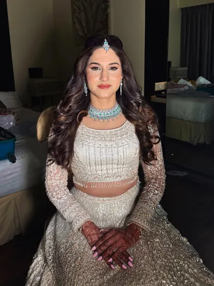 A Sangeet bride in a beautiful white and silver lehenga. The makeup is kept fresh and clean, with a pop of color on the lips.