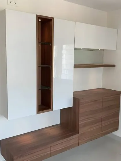 A modern crockery unit that combines glossy white cabinets with a dark wood frame. The open, lit niche in the center is a great spot for displaying special items.