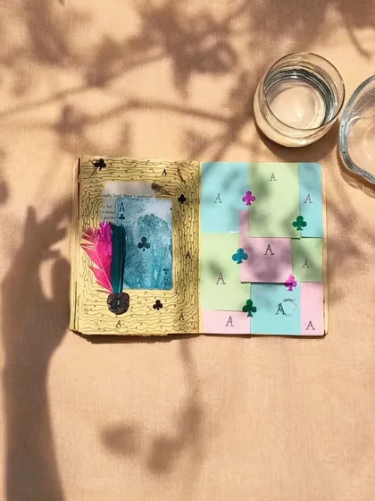 An art journal spread with a playful card theme, photographed with interesting shadows to create a dynamic image.