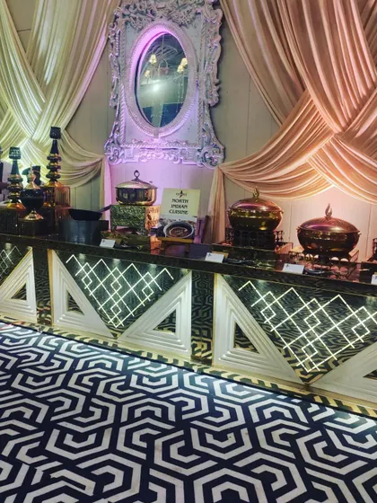 My North Indian cuisine station, set against a backdrop of beautiful drapes. The illuminated counters and traditional brass serving dishes create a warm and inviting look.
