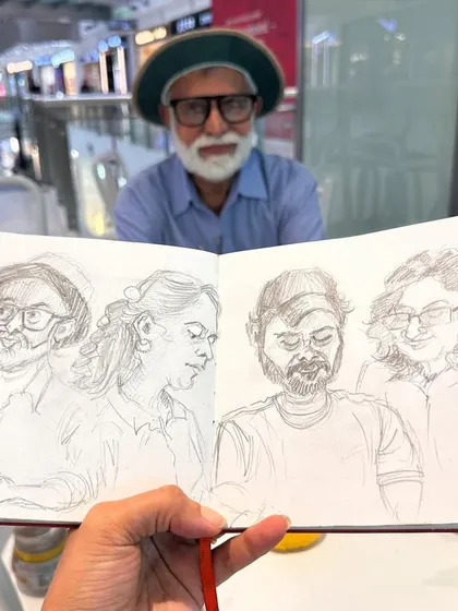 Holding up my sketchbook of portraits with one of my 'models', a fellow artist, in the background. Our sketch meets are a great chance to practice drawing people.