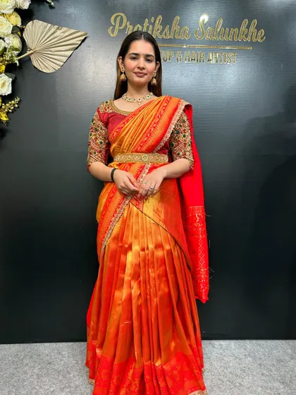 The full look of the orange and red half-saree. It's a vibrant and youthful style, perfect for celebrations.