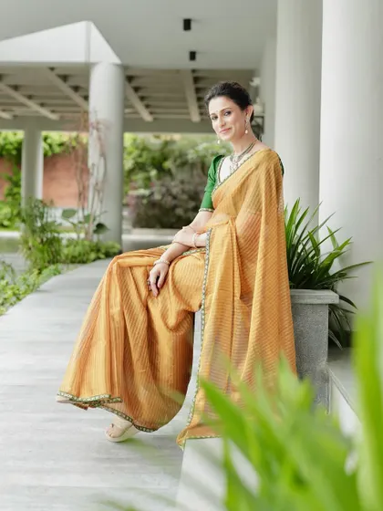 A beautiful golden tissue silk saree with a contrast green border, paired with a deep bottle green hand-embroidered blouse.