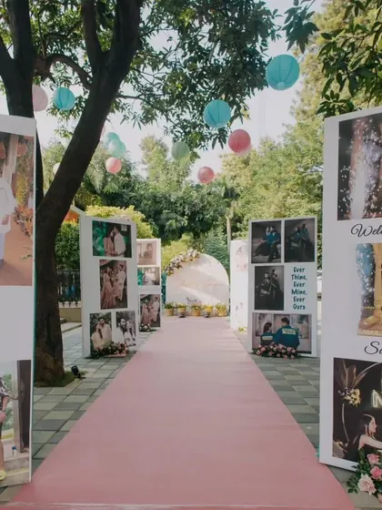 The entrance walkway to the Mehendi event, lined with large panels showcasing the couple's personal photos and journey, creating a 'walk down memory lane' for guests as they arrive.