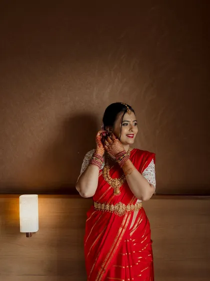 A bride getting ready in her room, adjusting her jewelry. These quiet, personal moments before the ceremony are an essential part of the wedding story.