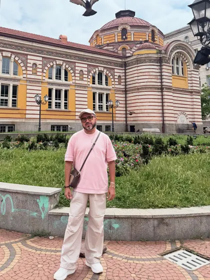 Another look from Sofia, pairing the pink tee and beige pants with a crossbody bag and cap for a relaxed, streetwear-inspired vibe.