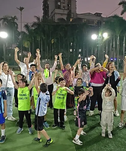 The whole party crew, kids and adults, with their hands in the air, celebrating a day of fun and games.