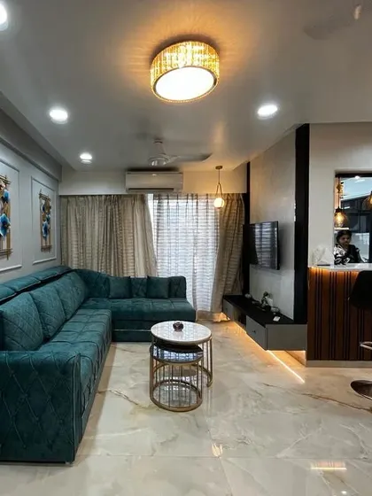 The living room in the evening, with all the lights on. The chandelier, spotlights, and indirect lighting in the TV unit and ceiling work together to create a warm and inviting ambiance.