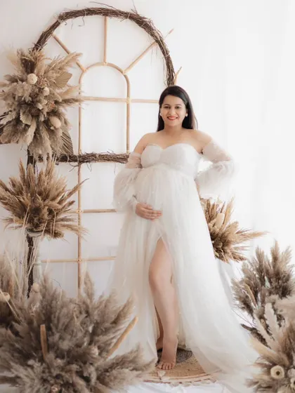 A radiant mother-to-be glowing in our airy, bohemian studio set. The beautiful white gown and rustic decor create a timeless and elegant maternity portrait.