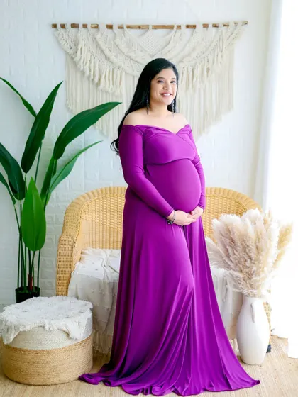 A vibrant, full-length portrait showcasing a stunning off-the-shoulder purple gown. We have a wide range of colors in our gown collection to match your personal style.