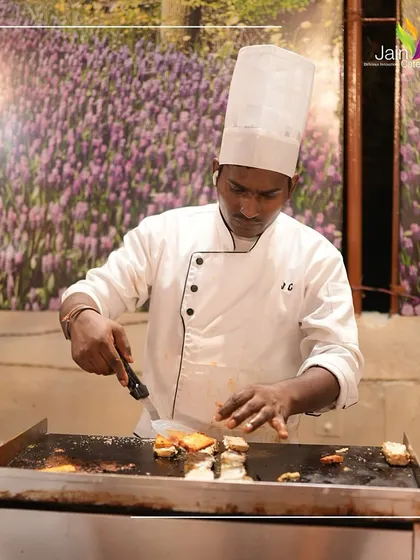 Cooking up serenity and flavour. A chef at a live station, grilling snacks to perfection, ensuring every bite is hot, fresh, and delicious.