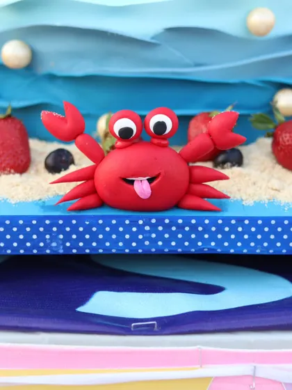 A silly and fun crab figurine made from bright red fondant. This little guy was part of a larger Little Mermaid dessert table, adding a touch of humor to the theme.