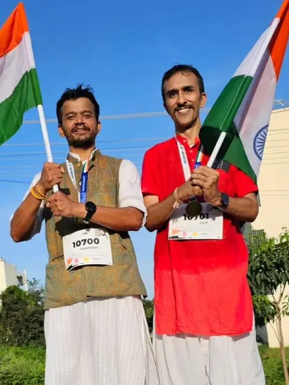 Two runners in traditional Indian attire proudly hold the tricolor flag after completing the 10km Freedom Run.