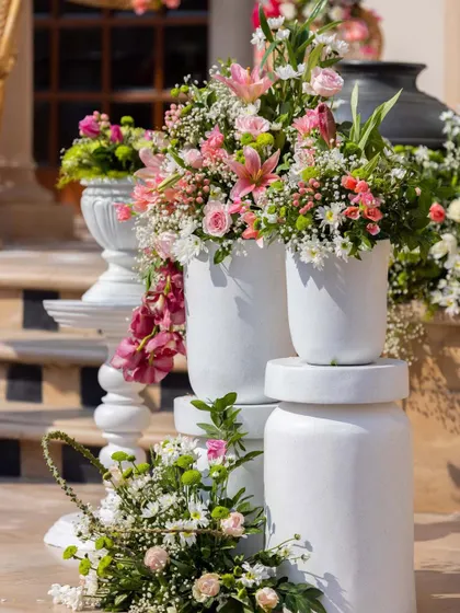 A close-up of the tiered floral arrangements on the steps, showcasing a mix of lilies, roses, and orchids in a fresh pink and white color palette.