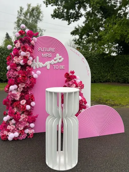 A fun and vibrant bachelorette party backdrop inspired by the popular Barbie theme. This setup includes custom pink arched panels, floral arrangements, and a 'Future Mrs' neon sign for the bride-to-be.