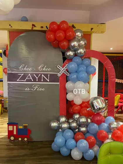 "Choo Choo, Zayn is Five!" A fun train-themed party setup with a custom arch backdrop and a red, blue, and silver color scheme.