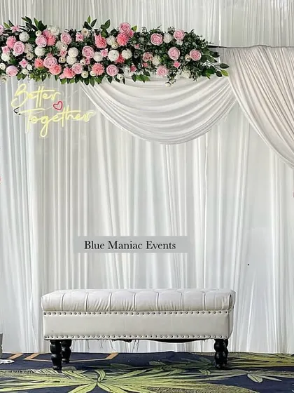 A beautiful example of a pink and white floral theme for an engagement. This setup uses a rectangular frame with an asymmetrical floral arrangement, a 'Better Together' neon sign, and a clean white backdrop for a fresh and modern feel.