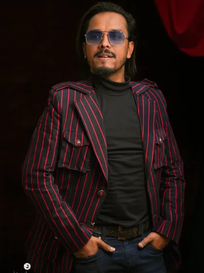 This custom-made pinstripe jacket features a unique design with multiple pockets and shoulder details. It's a modern take on a classic pattern, designed to be a standout piece.
