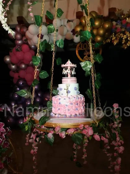 A close-up of the decorative swing used as a unique cake stand. The cake itself is a beautiful carousel, perfectly matching the whimsical and elegant theme of the event.