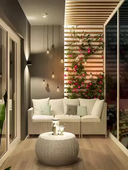 A sophisticated enclosed balcony, or loggia, with a comfortable sofa and ambient lighting. The climbing plants on the slatted wall add a touch of nature to this cozy, all-weather space.