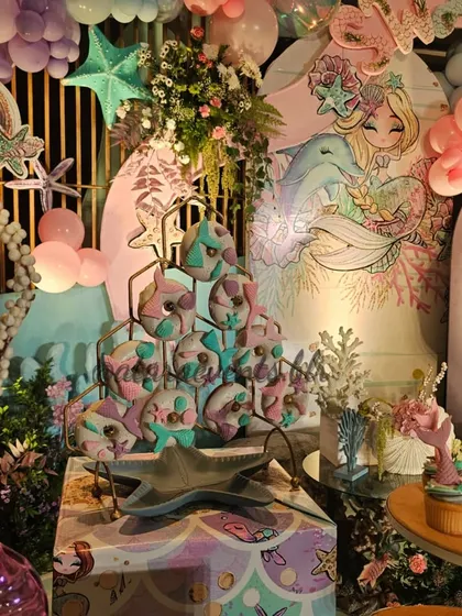 A dessert table from a mermaid party, featuring beautifully decorated donuts and other treats. The setup is adorned with sea-themed elements, creating a feast for the eyes as well as the palate.