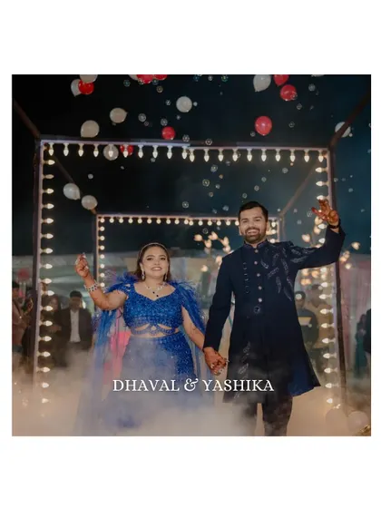 The couple makes a grand entrance through a tunnel of lights, surrounded by smoke and balloons. This shot captures the excitement and cinematic quality of their Sangeet celebration.