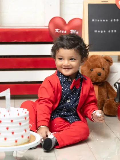 A classic pose with the birthday cake. This little one's bright smile and smart red bow tie make this Valentine's themed photo extra special.