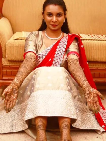 A full-length shot of a beautiful bride, showcasing her complete bridal look with mehndi on her hands and feet. She looks absolutely radiant.