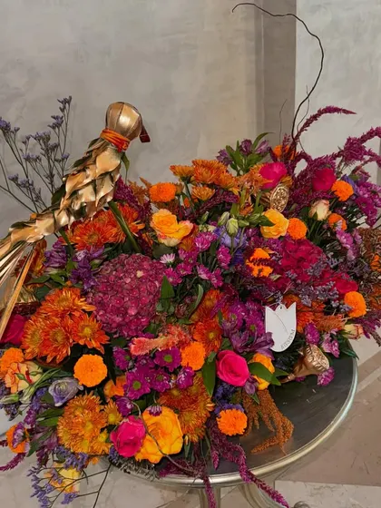 A vibrant Diwali delivery heading out the door. This arrangement is full of festive color, featuring bright oranges and pinks, and is accented with a golden decorative bird for an extra touch of flair.