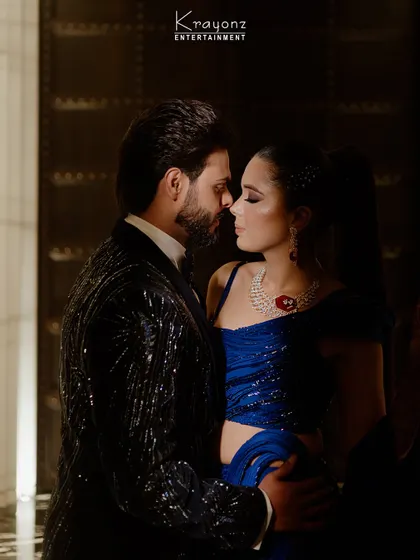 An intimate moment between the couple amidst the Sangeet night's excitement. The electric blue of the bride's outfit complements the dazzling stage lights.