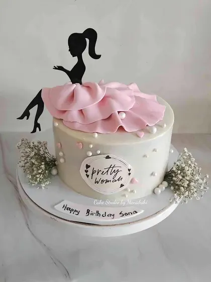 For a pretty woman, this cake is all about elegance. It features a silhouette topper, a delicate pink fabric-like drape, and sprigs of baby's breath for a soft, romantic feel.