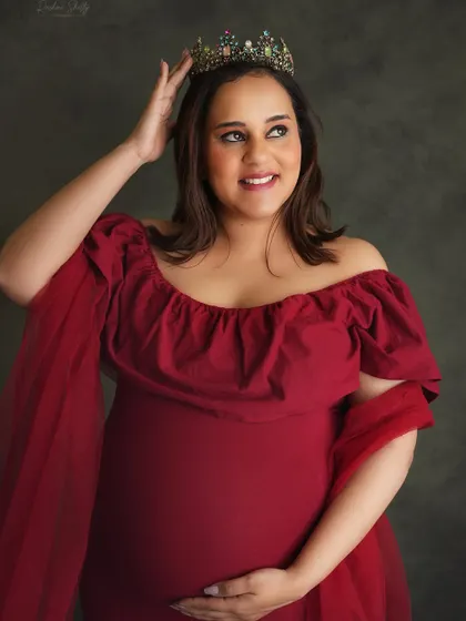A close-up on the queen. This shot focuses on the mom-to-be's happy expression as she adjusts her crown, radiating confidence and the joy of her pregnancy.