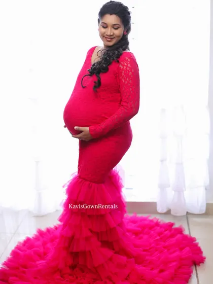 A bright and beautiful studio shot of a mom-to-be in a stunning pink mermaid gown.