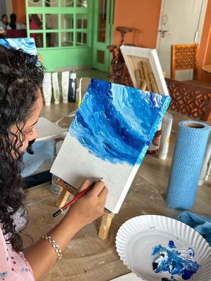 An artist working on the sky portion of her sunflower painting. The blended blues create a beautiful, dynamic background.