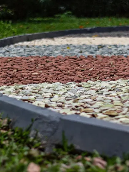 A close-up detail of the reflexology path shows the careful arrangement of smooth, rounded pebbles in distinct color bands. This highlights the craftsmanship involved in creating a surface that is both beautiful and therapeutic.