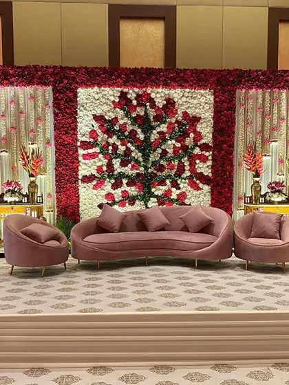The stage for a royal wedding reception, featuring a magnificent floral backdrop. A tree of life is meticulously crafted from red and white roses, creating a stunning and symbolic focal point for the couple.