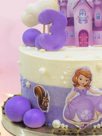 A close-up of the purple princess cake, showing the details of the castle and the cute woodland creatures joining the party.