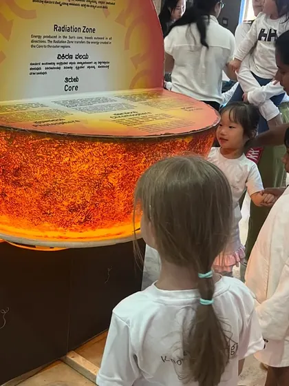 Children gather around a model of the sun's core, learning about astronomy in a hands-on, visual way.