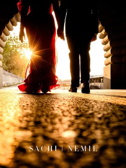 The sunburst creates a dramatic silhouette as the couple walks hand-in-hand through a Parisian archway, a perfect start to their pre-wedding story.