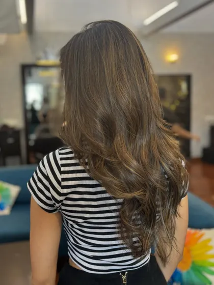A back view of this stunning balayage, showing how the light caramel tones are blended seamlessly into her natural brown base for a soft, dimensional look.