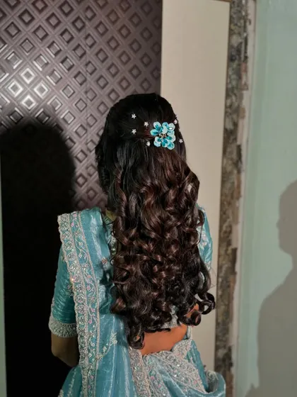 The soft curls and delicate hair accessory create a romantic and whimsical feel for this engagement look.