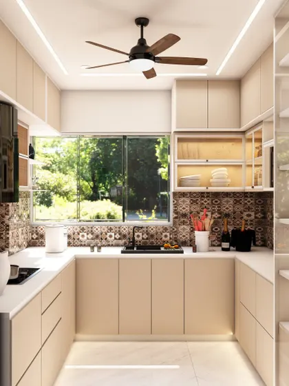 This U-shaped kitchen in our Matunga project features beige cabinets, a beautiful patterned tile backsplash, and glass-fronted upper cabinets for display.