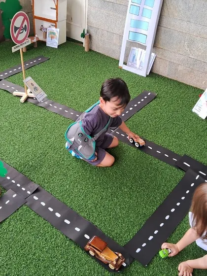 Two children play with wooden cars on the roads of our miniature town. This kind of play helps them understand concepts like traffic, directions, and community layouts.