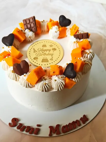A birthday cake celebrating the mango season. This one is decorated with fresh mango cubes, piped cream, and little chocolate hearts for a festive touch.